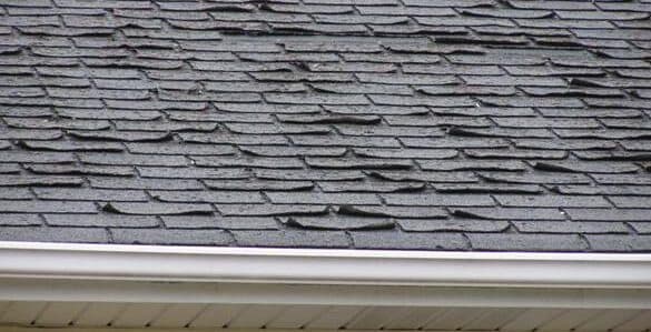 Aged asphalt shingles curling along a residential roof