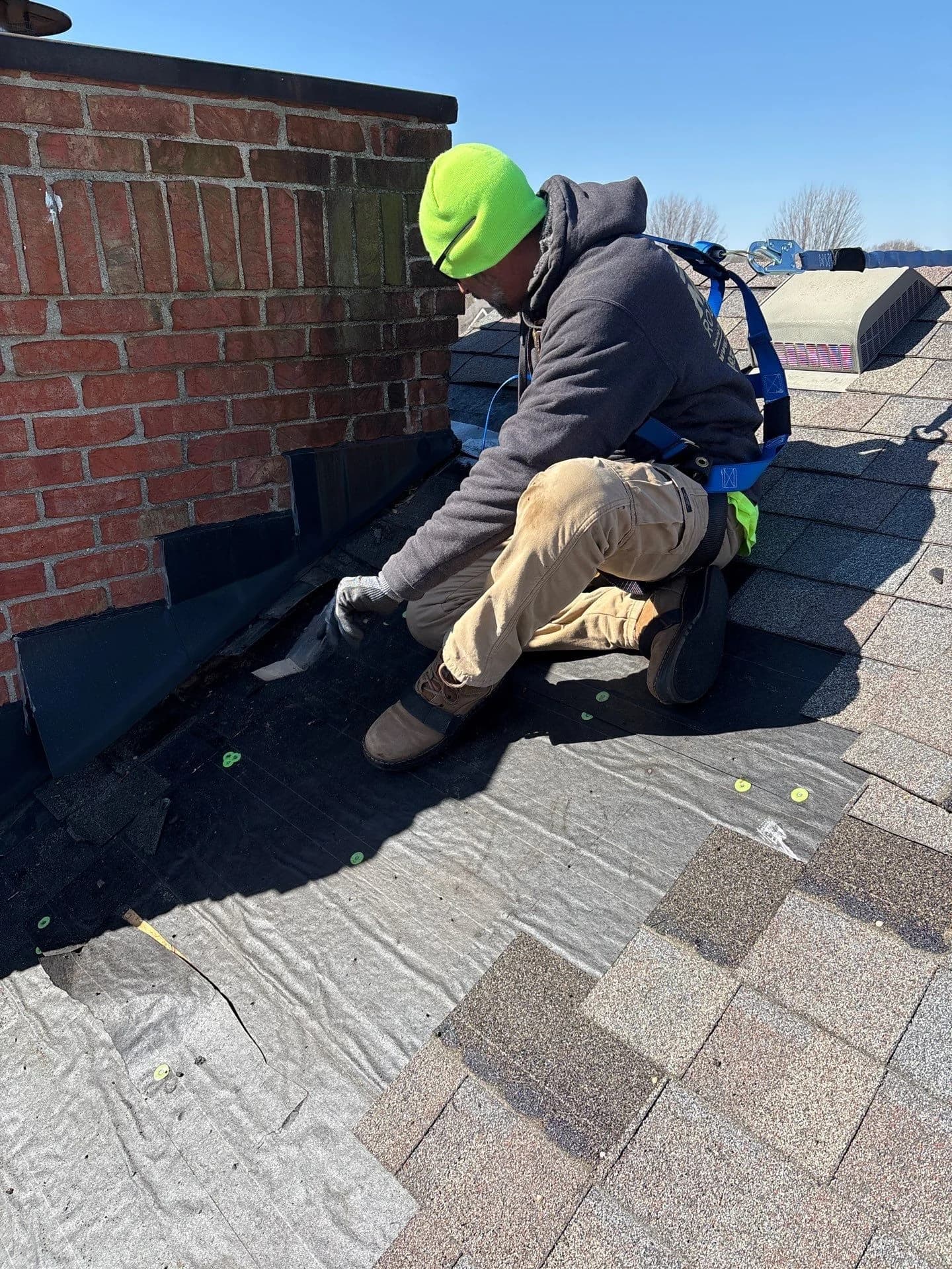 Roofer repairing chimney flashing after tracing a roof leak